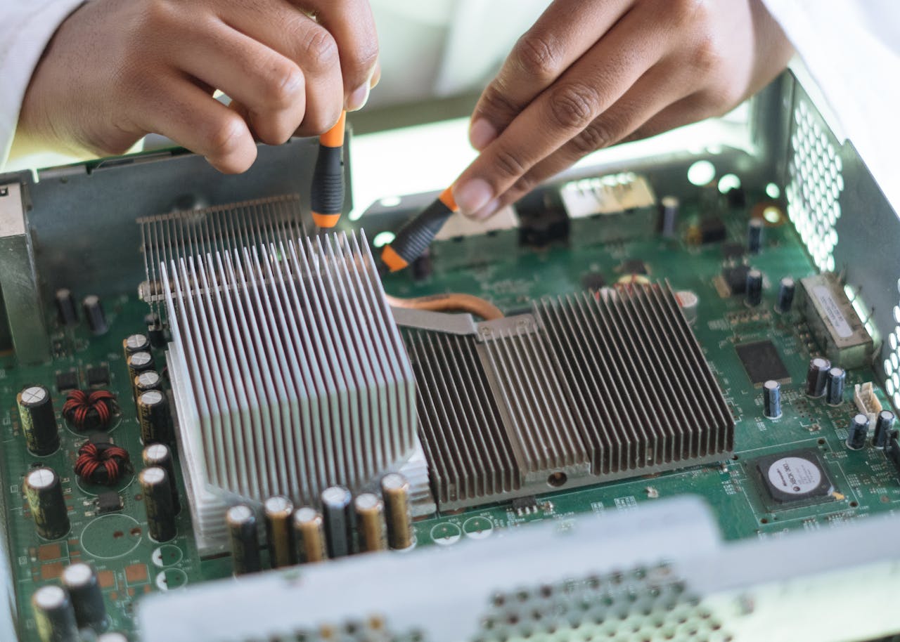who-we-are Close-up of a technician repairing a computer motherboard, focusing on microprocessor and heat sink.